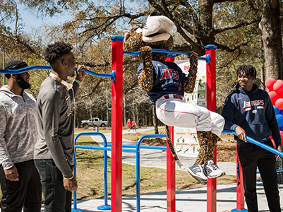 Southpaw doing a pull up on the Fitness trail with students watching.