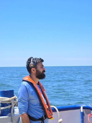 Ph.D. Student gazing out over the boat while wearing a life vest