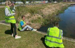 students wearing yellow vests for cleanup around waterway