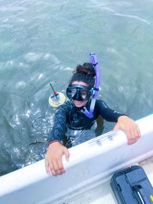 student hanging on the edge of a boat surfacing from a dive
