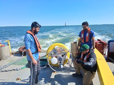 technician affixing bird spikes on a buoy tower for depoloyment while on a large boat