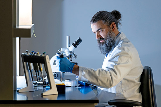 Researcher in lab using dropper with sample.