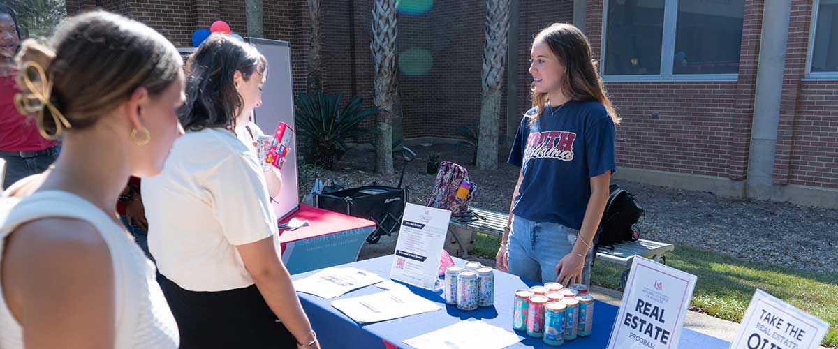 Student at real estate club table talking to students.