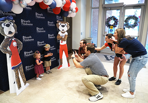 Family taking pictures of their kids in Alumni with cutouts of Southpaw and Ms. Pawla.