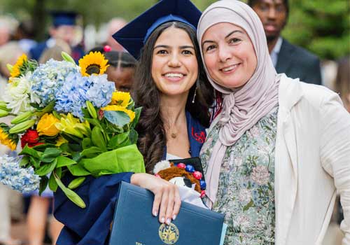 New graduate holding flowers with relative.