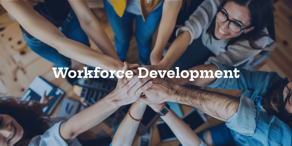People gathered around with their hands up and a workforce development banner over the picture