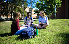 Three students sitting on grass