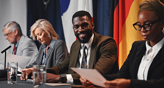 Group at table with flags behind them.